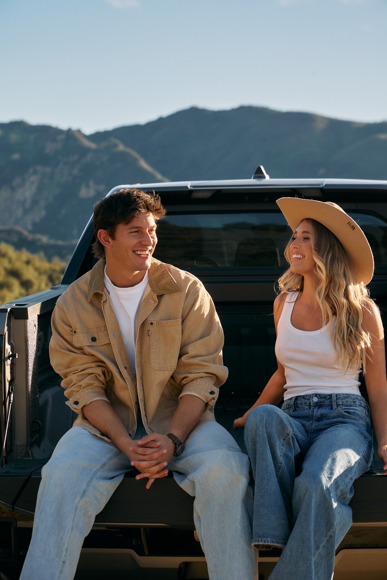 Couple on truck tailgate, mountains